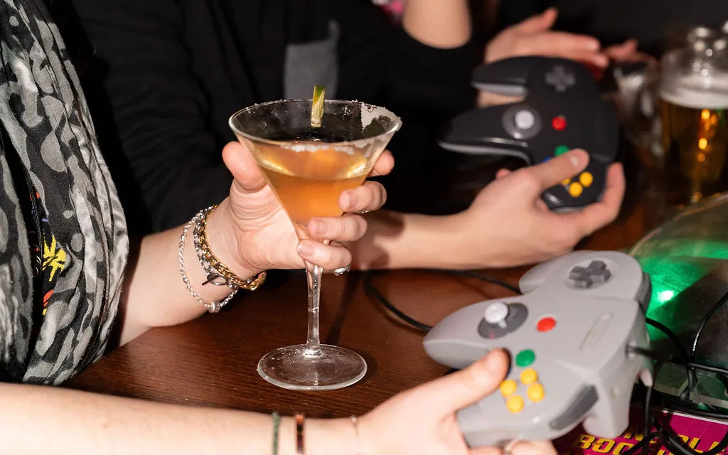Cocktail and N64 controllers in hand during a booth session at Bartronica