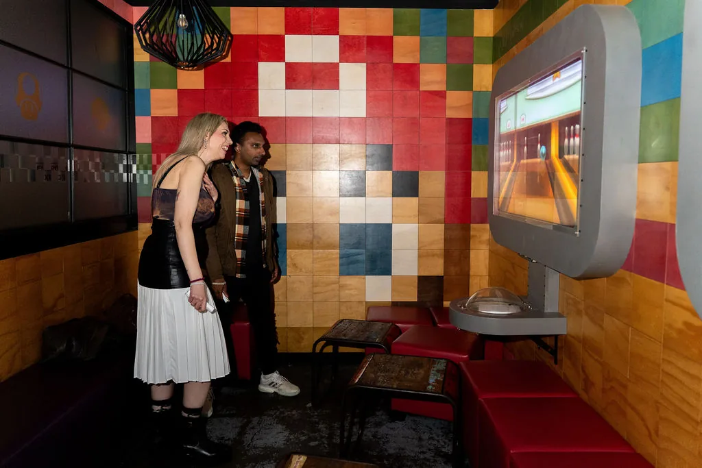 Two friends playing Wii bowling in a booth at Bartronica