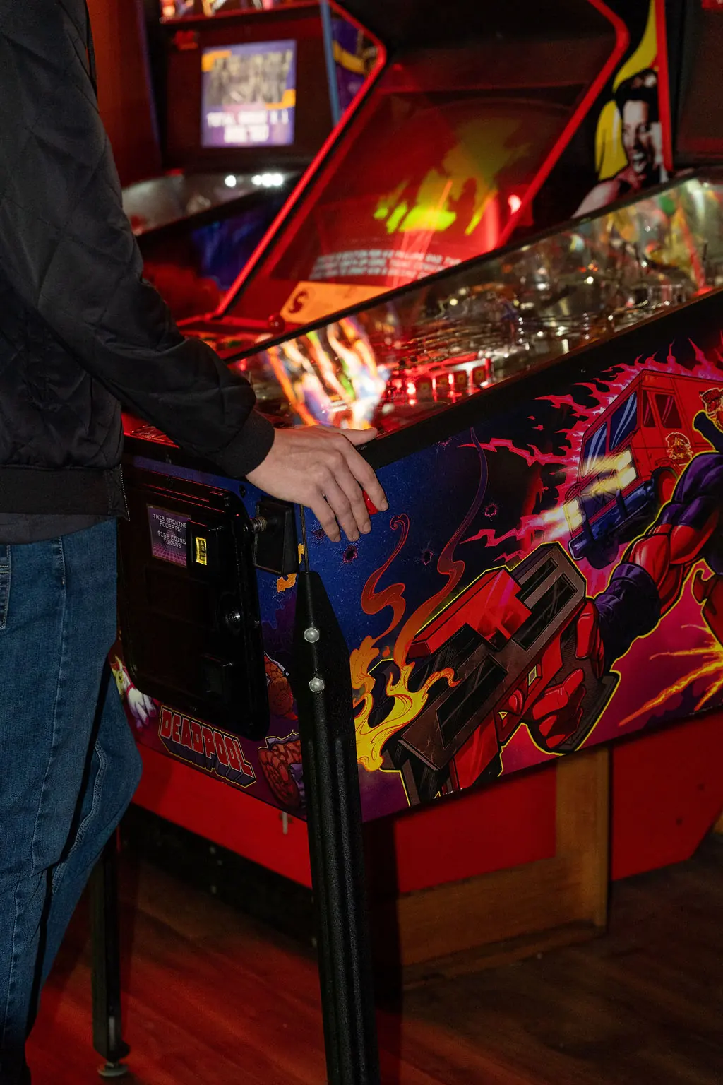 A guest playing the Deadpool pinball machine at Bartronica